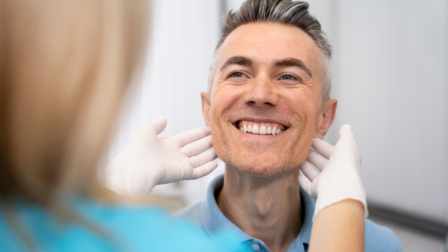 A friendly Turkish dentist in a modern clinic consults with two relaxed, smiling adult patients.
